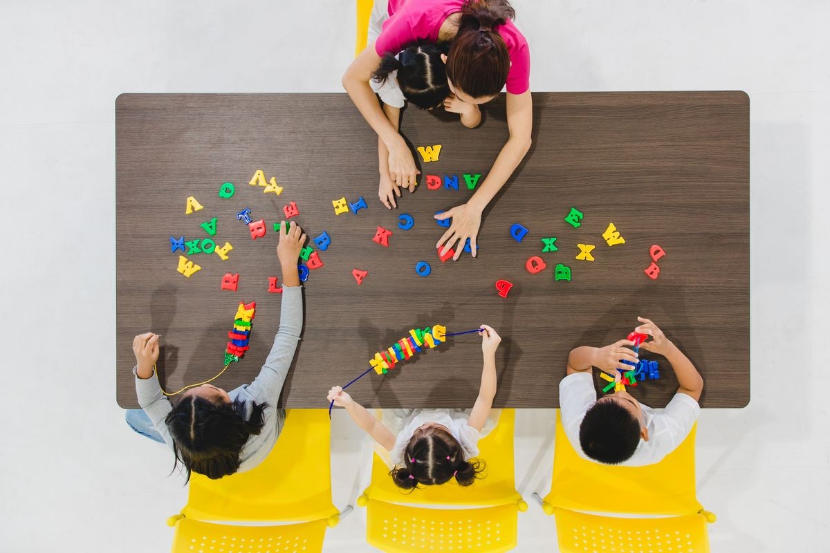 Group of kids and teacher playing colorful toys in classroom. Concept for happy and funny learning, brain development activities in school free time.